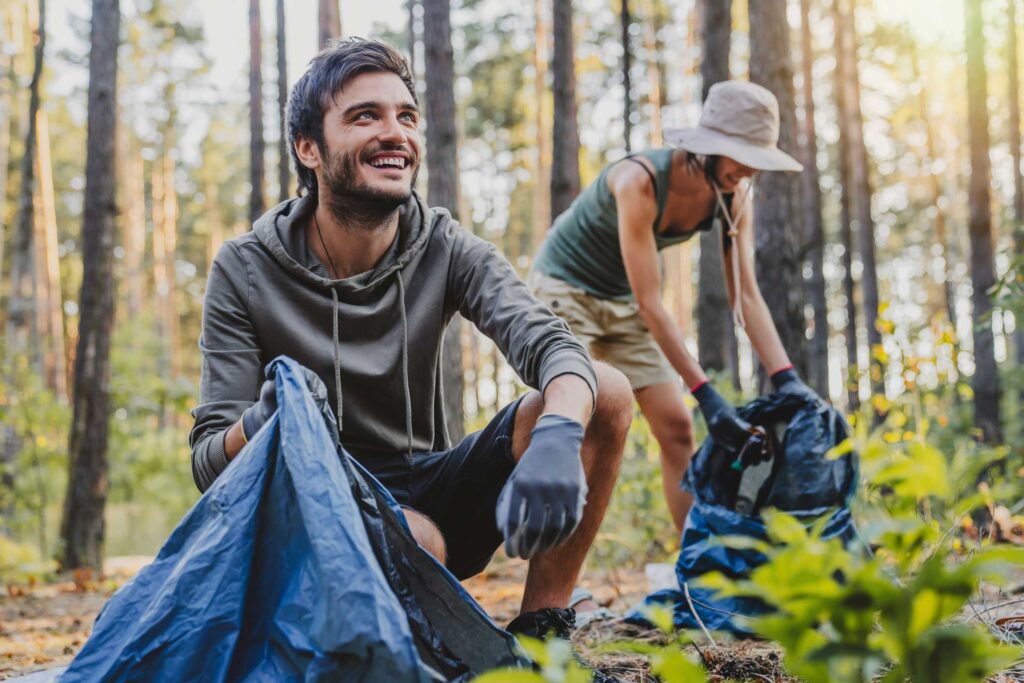 two people picking up trash in a forest