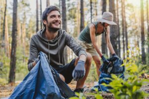 two people picking up trash in a forest