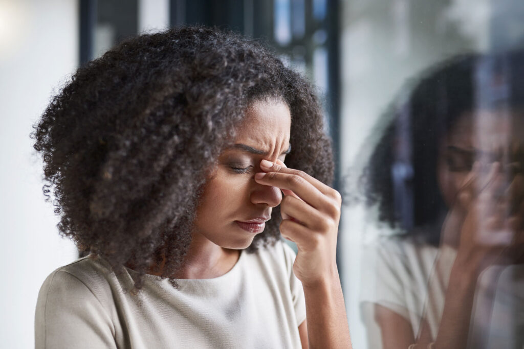 woman with headache holding her sinuses
