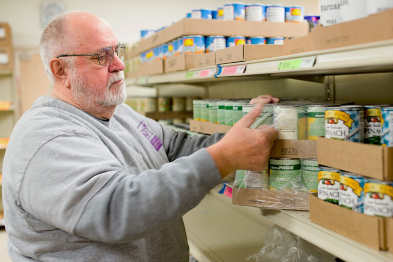 A man stocks cans of food at foodbank